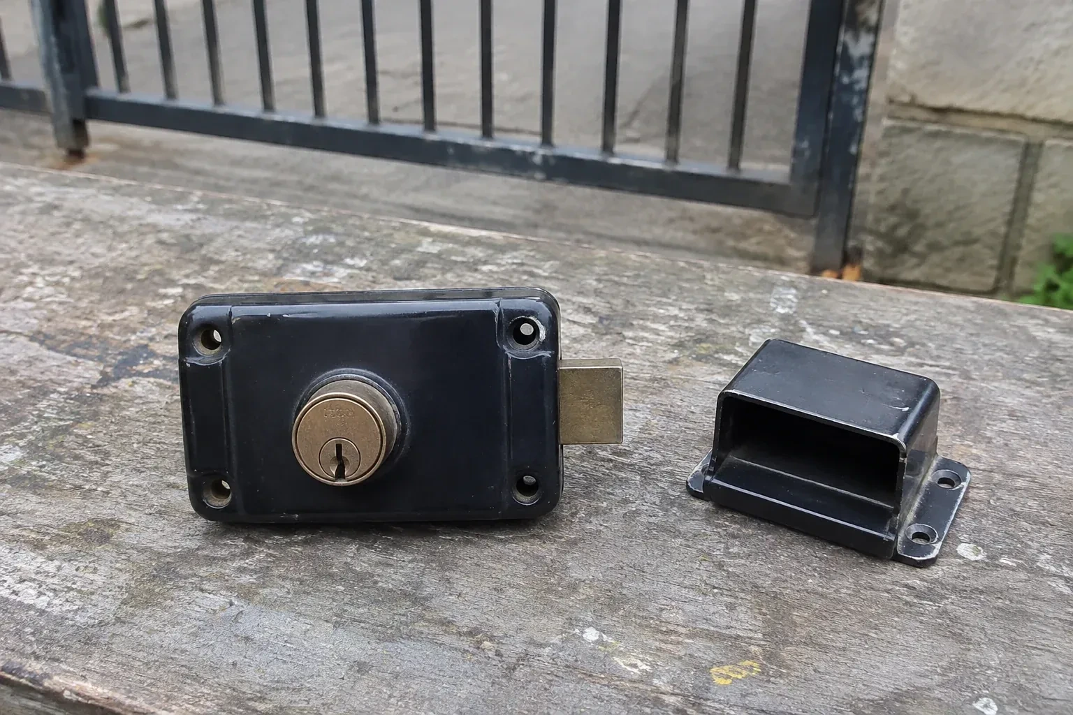 Detached rim gate lock and separate box keeper on an outdoor workbench. — Gate & Building Entry Locks, Cambridge